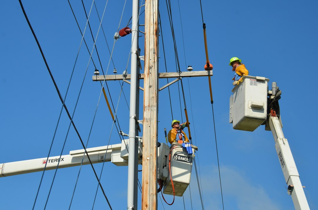 Utility line crews repairing storm-damaged electrical equipment on a residential street