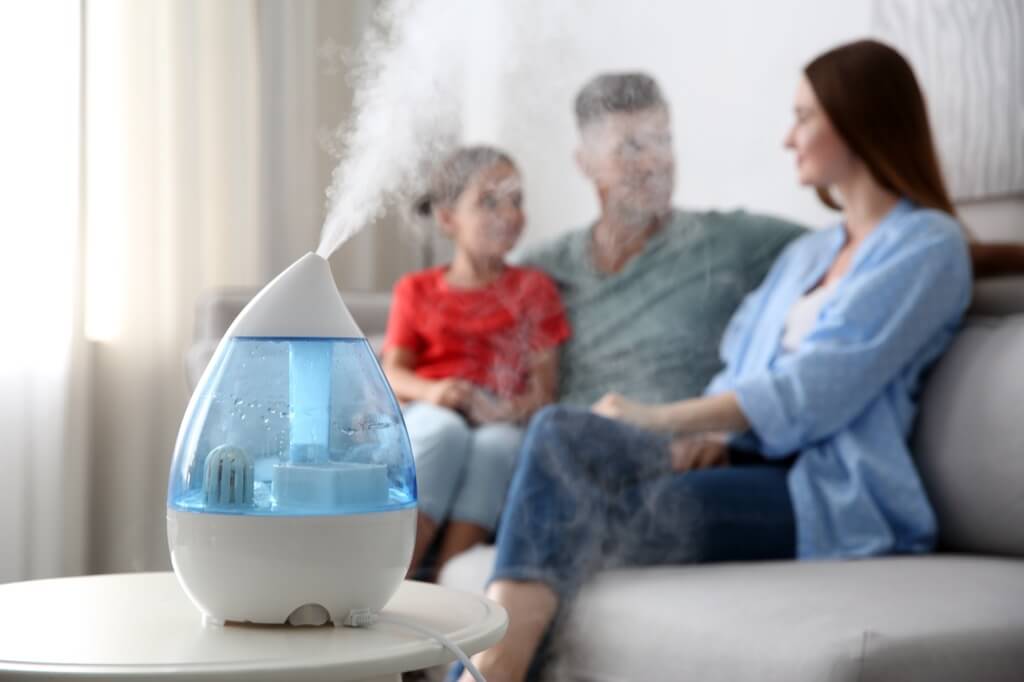 Humidifier running in a living room with family, illustrating "Should I Run a Humidifier with My Air Conditioner?"