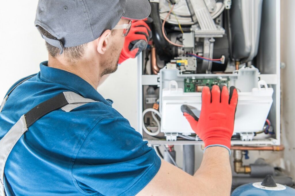 Technician repairing furnace to reduce furnace maintenance cost and prevent future repair expenses