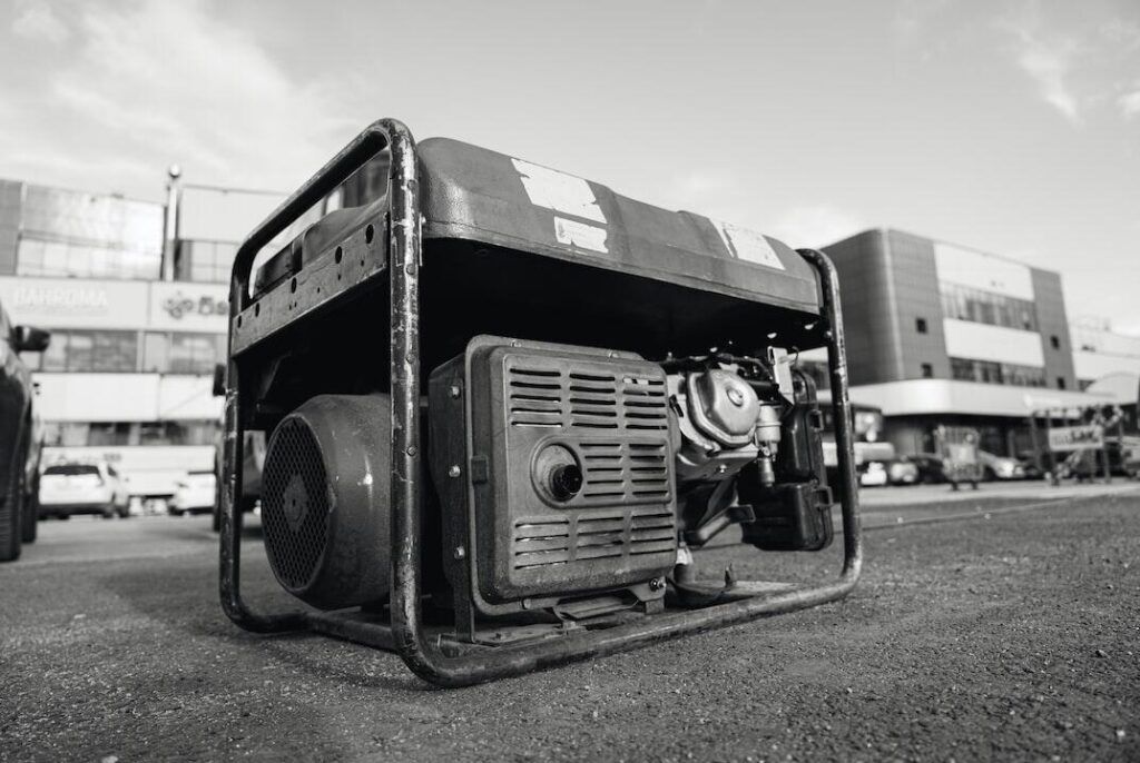 Portable fuel-powered generator with protective frame sitting outdoors on pavement