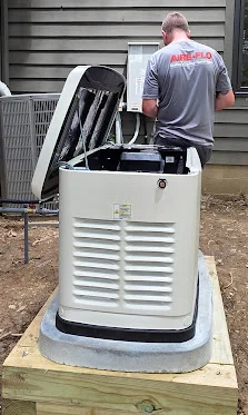 Professional technician installing a standby generator on a concrete pad outside a Columbus home